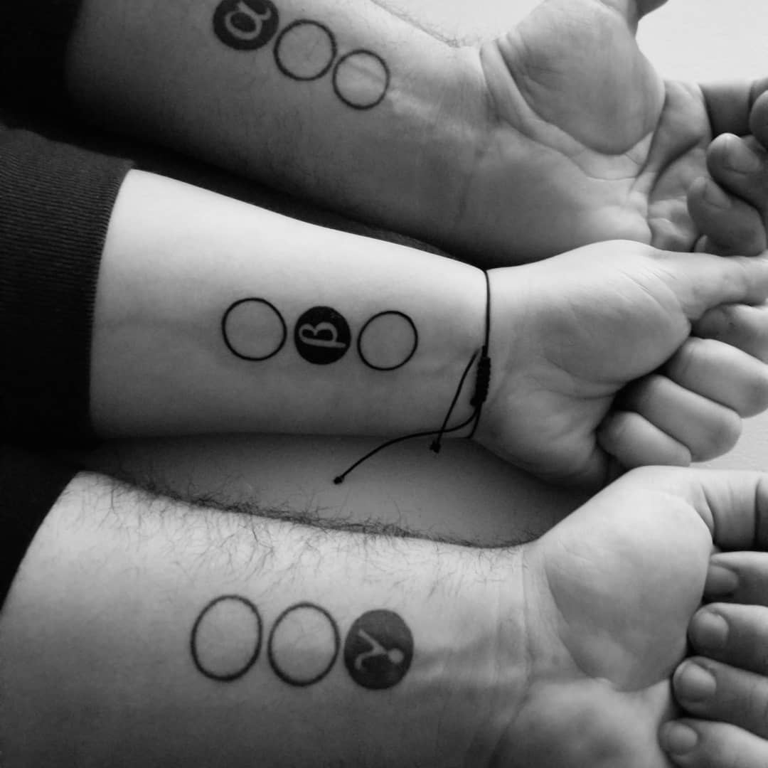 Three wrists with tattoos featuring circles that contain the letters A, B, and Y in black and white